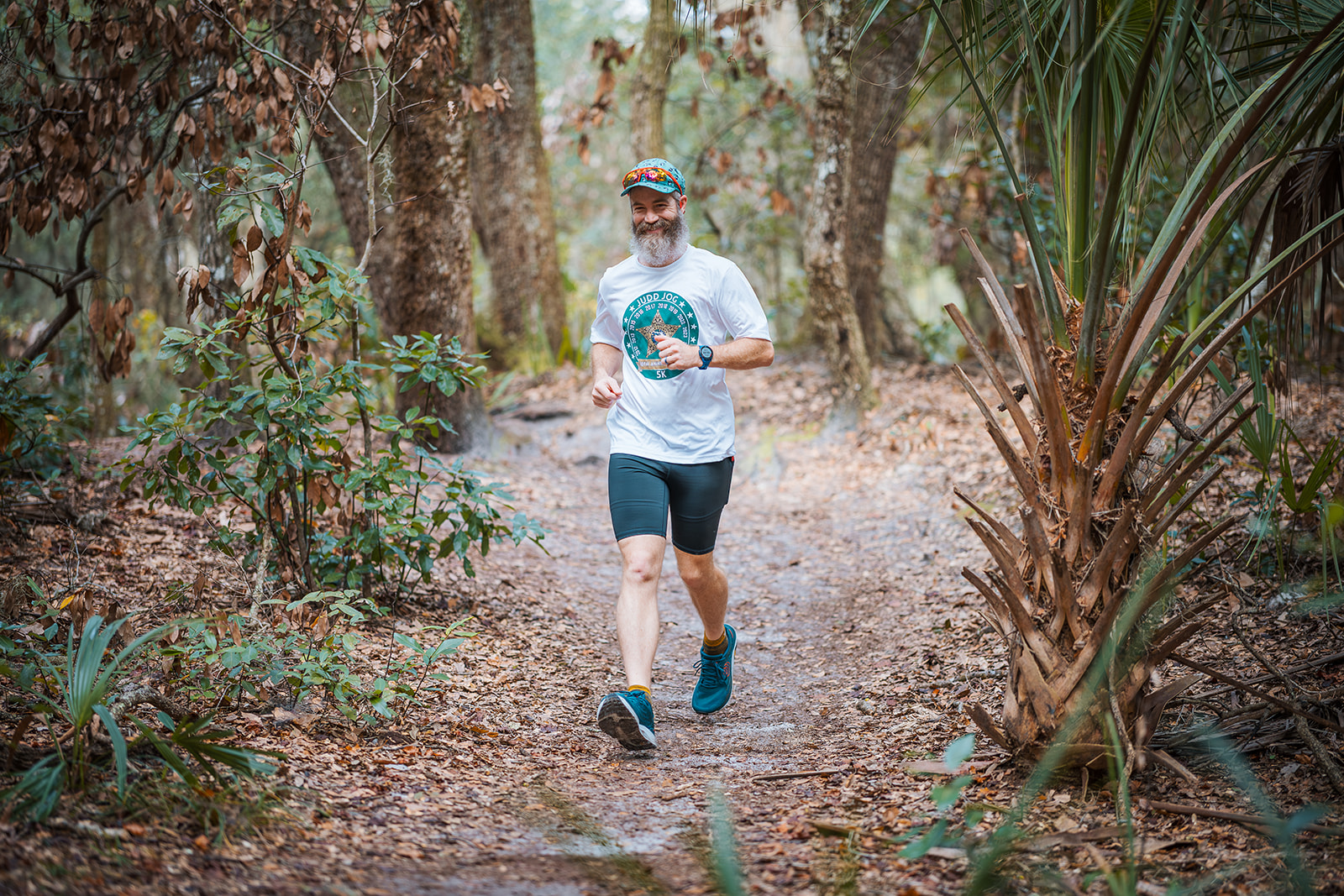 A runner on a leaf covered trail through palmetto and live oak
